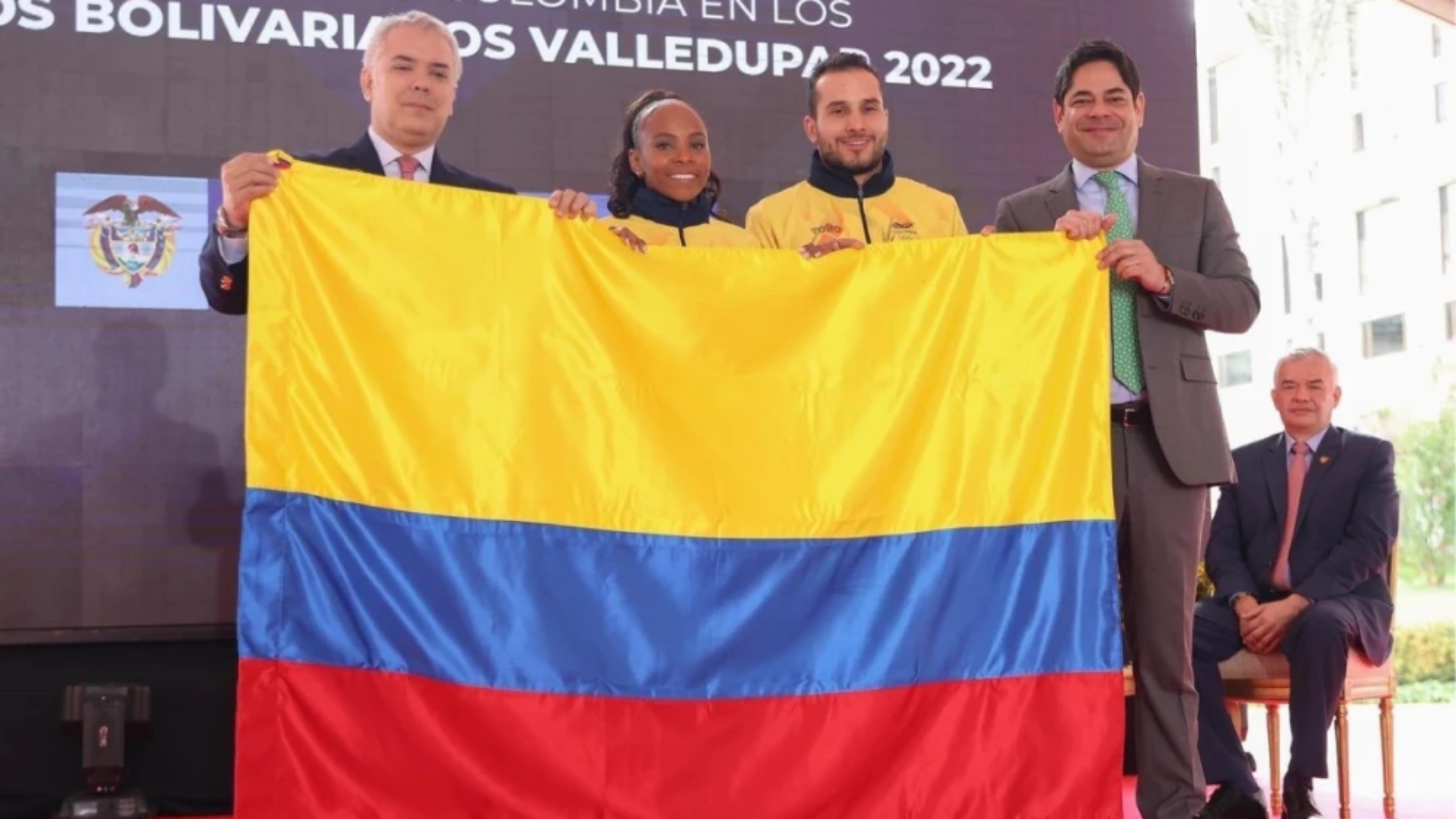 Presidente de Colombia entregando bandera a deportistas.